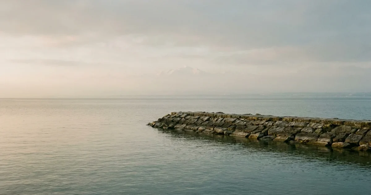 Rives du lac Léman à Versoix avec brise-lames en pierre et eau calme